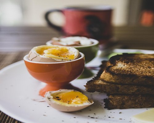 Traditional kopitiam breakfast with soft boiled eggs and morning beverage on a wooden table