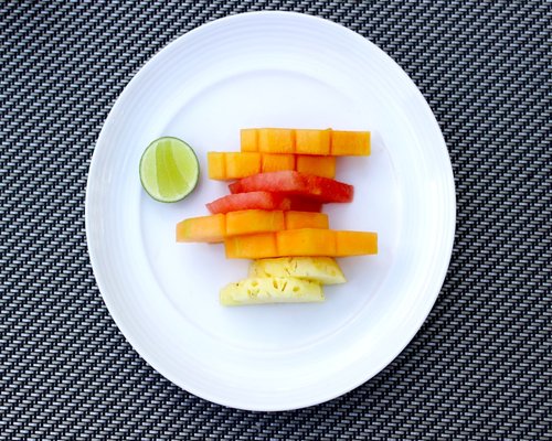 Sliced fresh tropical fruits including local papaya and mango on a ceramic plate