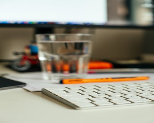 Pure clean drinking water in a glass bottle on a workspace desk with soft natural reflections