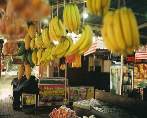 A variety of fresh tropical fruits and green local vegetables displayed beautifully at a traditional Malaysian morning market